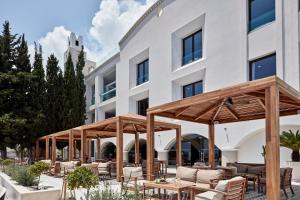 
a patio area with chairs, tables and umbrellas at Esperos Village Blue & Spa - Adults Only in Faliraki
