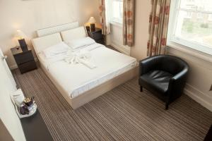 ein Schlafzimmer mit einem weißen Bett und einem schwarzen Stuhl in der Unterkunft New Market Ale House in London