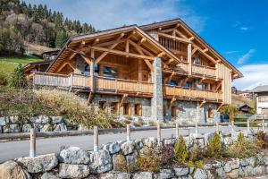 a large wooden house with a fence in front of it at Abachi Chalet Les Gets - by EMERALD STAY in Les Gets