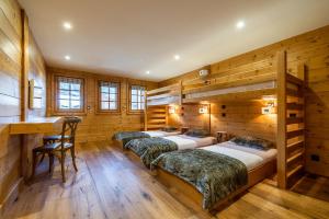 four beds in a room with wooden walls at Abachi Chalet Les Gets - by EMERALD STAY in Les Gets