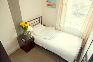 een kleine slaapkamer met een bed en een raam bij New Market Ale House in Londen