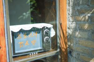 uma televisão velha numa janela ao lado de uma parede de tijolos em Autumn Inn em Yangshuo