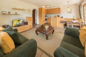 een woonkamer met een bank en een tafel en een keuken bij Försterli West in Grächen