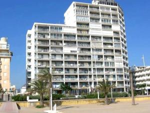 a large white building with palm trees in front of it at BONAIRE - PRIMERA LÍNEA DE PLAYA in Playa de Gandia