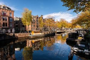 a canal with buildings and boats in a city at Prinsengracht Canal Studios in Amsterdam