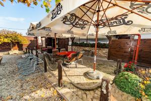 een patio met een tafel en stoelen onder een parasol bij Bástya Panzió és Étterem in Mezőpeterd