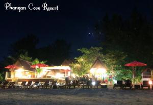 un grupo de sillas y sombrillas en una playa por la noche en Phangan Cove Beach Resort en Srithanu