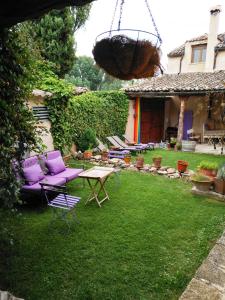 un patio trasero con muebles morados y una cesta colgante en La Casona de Castilnovo - Gay Men Only, en Valdesaz