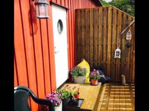 un patio trasero con un edificio rojo con flores y plantas en Handkleppveien 26 - Fishermans cabin, en Straume