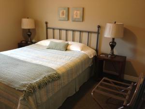 a bedroom with a bed and two lamps and a chair at McIntyre's Cottages in Baddeck Inlet