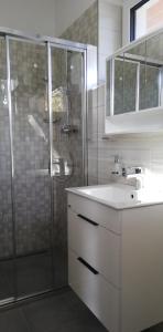 La salle de bains est pourvue d'une douche, d'un lavabo et d'un miroir. dans l'établissement Slope Apartments Lipno, à Lipno nad Vltavou