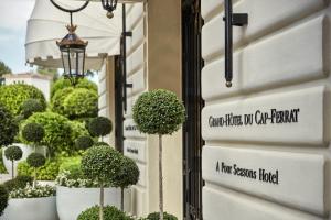 a sign on the side of a building with potted trees at Grand-Hôtel du Cap-Ferrat, A Four Seasons Hotel in Saint-Jean-Cap-Ferrat