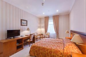 a hotel room with a bed and a desk and a television at Baltic Star Hotel in Petergof