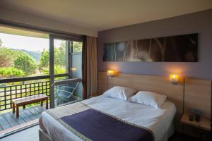 a bedroom with a large bed and a large window at Hôtel Castell'Verde in Porto-Vecchio
