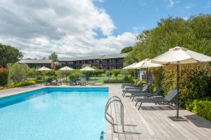 a swimming pool with lounge chairs and umbrellas at Hôtel Castell'Verde in Porto-Vecchio