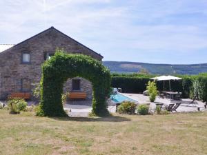 una casa de piedra con un arco de hiedra en un patio en Gorgeous holiday home in Stoumont with garden, en Stoumont