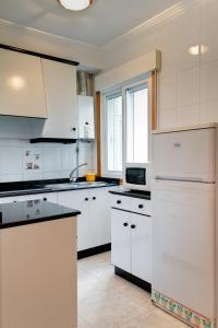 a kitchen with white cabinets and a refrigerator at Duerming Bolera Pico in Portonovo +18 photos