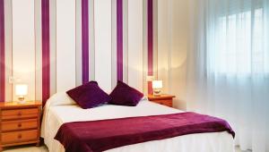 a bedroom with a bed with purple sheets and a window at Duerming Bolera Pico in Portonovo
