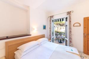 a bedroom with a white bed and a balcony at Hotel Europa in Ischia