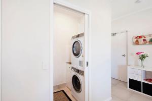 a white laundry room with a washer and dryer at Durramboi Luxury Apartment in Noosaville