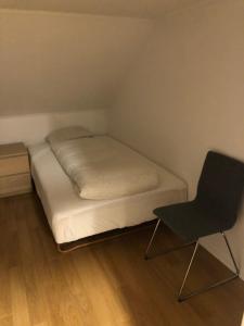 a small bedroom with a bed and a chair at Birkebeiner Apartment in Bergen