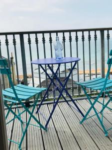a blue table and two chairs on a balcony with the ocean at 'Kaia' Beach Vista, Ventnor Beach in Ventnor