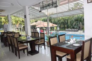a dining room with a table and chairs and a pool at Mrugavani Resort & Spa in Hyderabad