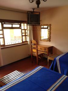 帕茨誇羅的住宿－波薩達德拉薩魯德酒店，卧室配有一张床、一张书桌和窗户。