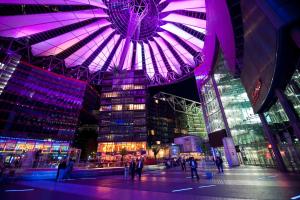 un gran edificio con iluminación púrpura en una ciudad por la noche en Suite im Sony Center am Potsdamer Platz, en Berlín