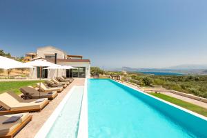 a swimming pool with lounge chairs and a villa at Elements Villa in Galangádhos