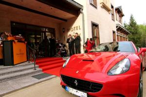 a red car parked on a red carpet in front of a building at Retro Riverside Wellness Resort in Karlovy Vary
