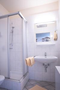 a white bathroom with a shower and a sink at Hotel Krug in Gumpoldskirchen