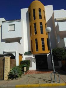 un edificio blanco y amarillo con una torre de reloj en Apart Club la Barrosa en Chiclana de la Frontera