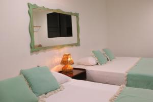 una camera con 2 letti, uno specchio e una lampada di Punta Piedra Beach Posada a Tulum