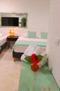 a room with two beds and a red flower on a table at Punta Piedra Beach Posada in Tulum