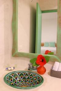 lavabo con espejo verde y flor roja en Punta Piedra Beach Posada, en Tulum