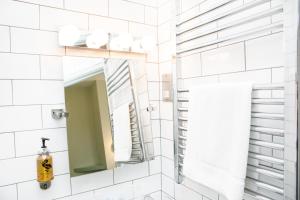 a bathroom with a mirror and white tiles at The Lerryn in Falmouth