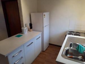 uma cozinha com um frigorífico branco e um lavatório em Dianella · Affordable & comfortable close to the city & shops em Perth