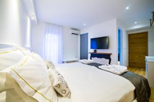 a bedroom with a large white bed and a flat screen tv at MEMENTO B&B Piran in Piran