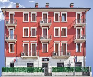 a red building with balconies on a street at Verona Class ApartHotel "Residenze del Cuore" in Verona