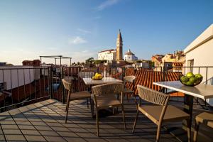 a patio with tables and chairs on a balcony at MEMENTO B&B Piran in Piran