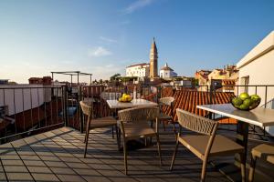 un patio con mesas y sillas en el balcón en MEMENTO B&B Piran, en Piran