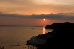 um pôr-do-sol sobre o oceano com o sol no céu em A due passi dal mare em Realmonte