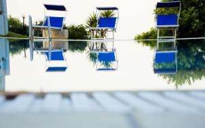 une rangée de chaises bleues assises dans une piscine d'eau dans l'établissement Tenuta Su Vrau, à Posada