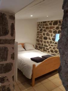 a bed in a room with a stone wall at La maison D'Orée in Polignac
