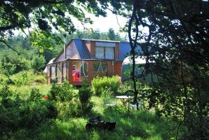 una casa en medio de un campo de hierba en Meadowsweet Forest Lodge en Fintown