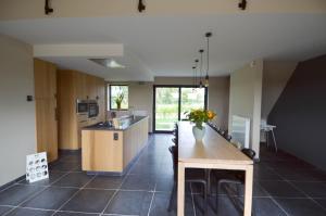 a large kitchen with a wooden table and a counter at Fermette de bobonne in Poperinge