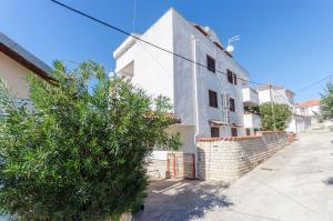 Una casa blanca con un árbol delante. en Apartments Little spring, en Vodice