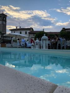 a swimming pool with a clock tower in the background at La Locanda Del Grop in Tavagnacco