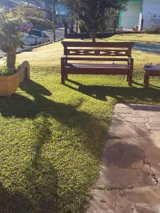 un banco del parque sentado en el césped junto a una acera en Pousada Casa Amarela, en Canela